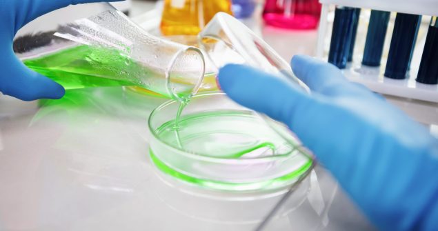 Researcher is dropping the reagent into test tube for reaction testing in chemical laboratory